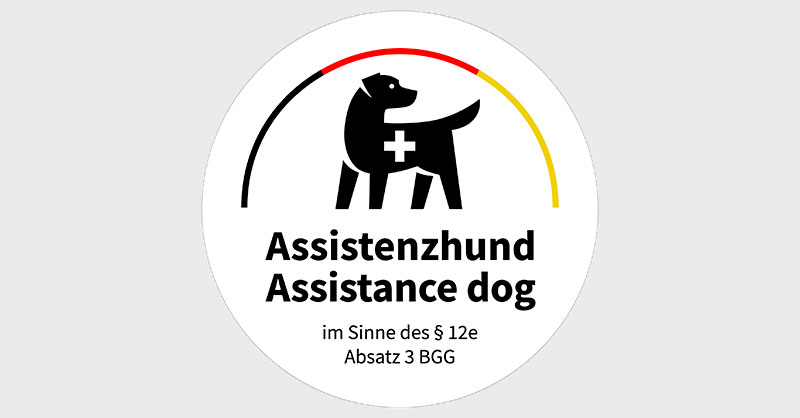 Kennzeichen aus der Assistenzhundeverordnung - ein Hund daüber ein Halbkreis in schwarz, rot, gold und darunter der Schriftzug Assistenzhund im Sinne des § 12e Absatz 3 BGG