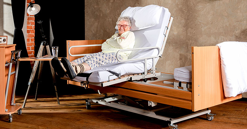 Frau sitzt freudestrahlend im Aufstehbett