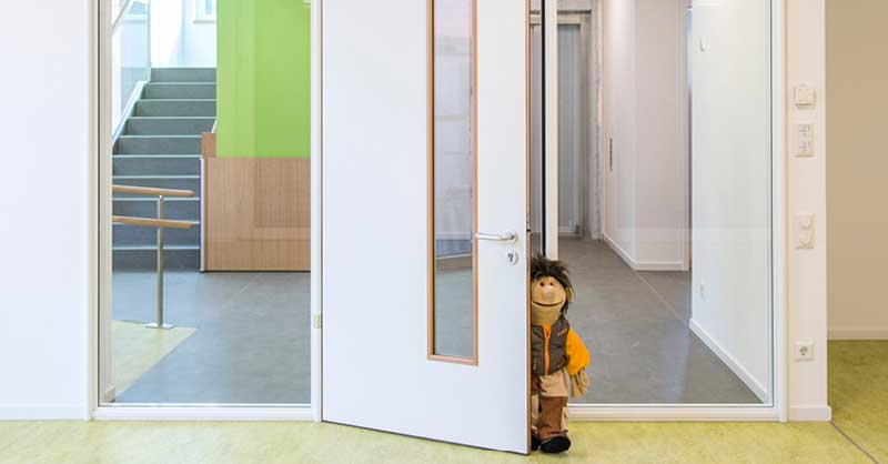 kleines Kind an einer geöffneten Tür zum Treppenhaus