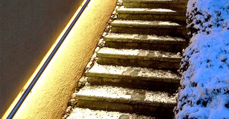 Frohes Fest(halten) beleuchteter Handlauf an verschneiter Treppe